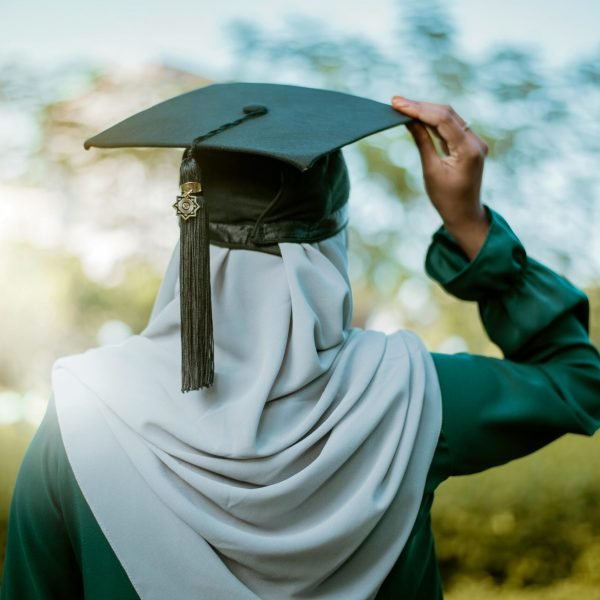 A hijabi woman celebrates graduation outdoors with an academic cap under the summer sky in Maldives.